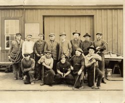 As far as I know, this is a photo of the crew at the Blacksmith Shops for the Southern Pacific Railroad in Oakland, California.  My grandfather (front and center with the rakishly tilted hat) worked for the railroad for some small portion of his life.  His draft card for World War I listed him at the railroad in the blacksmith shop.  By the '30's, he'd started a laundry business elsewhere in Oakland.
He'd emigrated from the Azore Islands to California in around 1915, following other brothers and sisters who'd already left the impoverished islands for the opportunity of the United States.  I can't imagine he was too many years off the boat when this photo was taken, a new immigrant settling into life in California.
I've always liked this, both as a cool posed shot of an industrial shop and by the tools of the trade each worker carries (especially the welder to the far left).  Unlike all the school photos that got saved, it's like every guy in the photo has some emotion on his face, and some story behind it.  Why's the big guy at the right side in the front row look like a superhero, so sure and happy?  What's the Richard Gere look-alike (the welder) thinking?  What's the guy second from the left in the front row staring at off in the distance? View full size.
(ShorpyBlog, Member Gallery, Railroads)